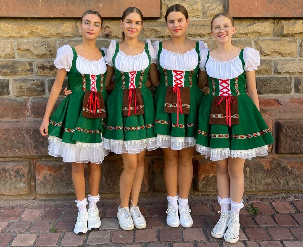 Vier lächelnde Tänzerinnen in grünen Dirndl