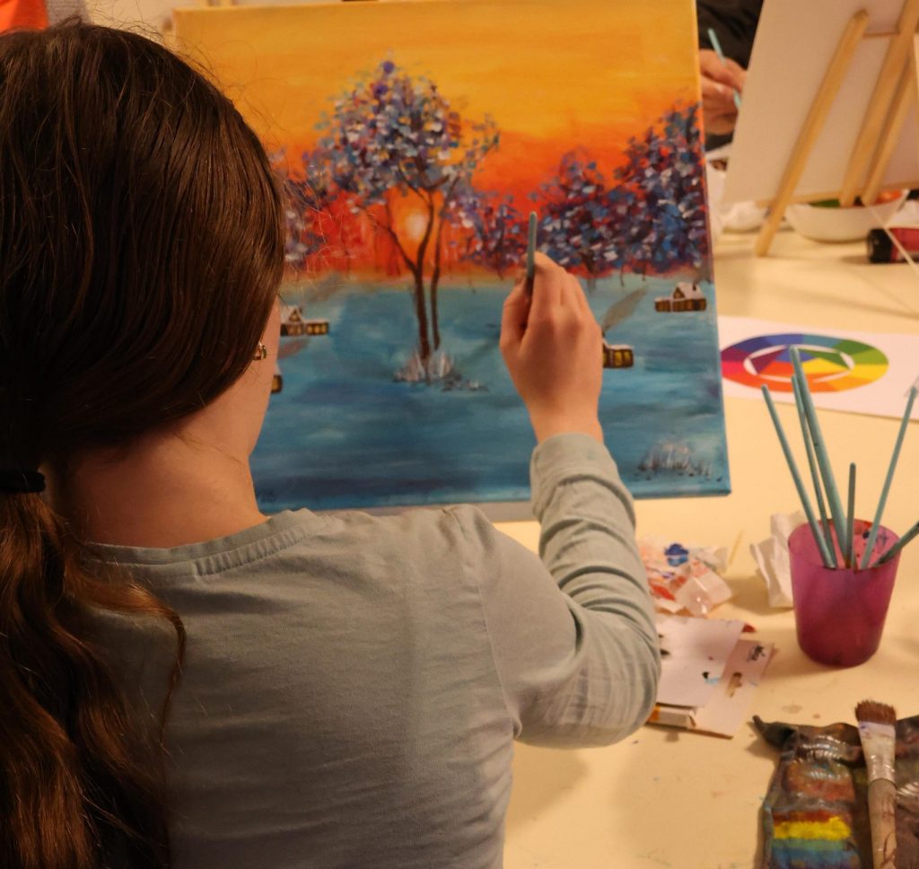 Kind malt mit Acrylfarben auf einer Leinwand